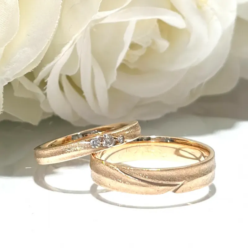 Individuell gefertigte Trauringe Berlin in Gold mit Diamant vor weißer Rose